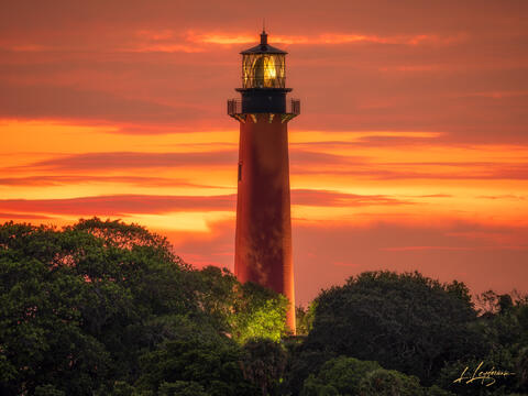 Jupiter Lighthouse at sunset with fiery orange clouds.