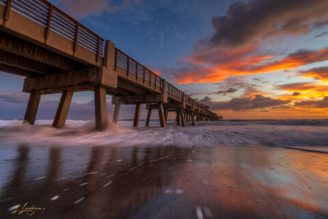 Pastel waves washing over sand at sunrise near Juno Beach Pier.
