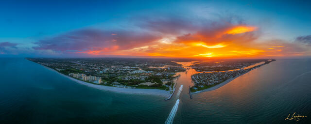 Aerial drone photograph of boats leaving Jupiter Inlet at sunset with vibrant orange and blue skies over Juno Beach Pier in Palm Beach County, Florida.