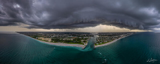 Aerial drone photograph of a dramatic shelf cloud rolling over Juno Beach Pier and Jupiter Inlet in Palm Beach County, Florida, with dark atmospheric skies abov
