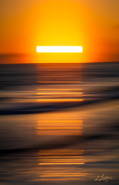 A radiant sunrise over the ocean in Jupiter, Florida, captured as a golden brushstroke of light across sea and sky. Fine art seascape photography print by Lawre