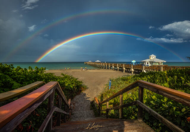 A double rainbow arcs above Juno Pier on the Florida coast as the storm clears. The vibrant colors contrast against the fading storm clouds, symbolizing light a