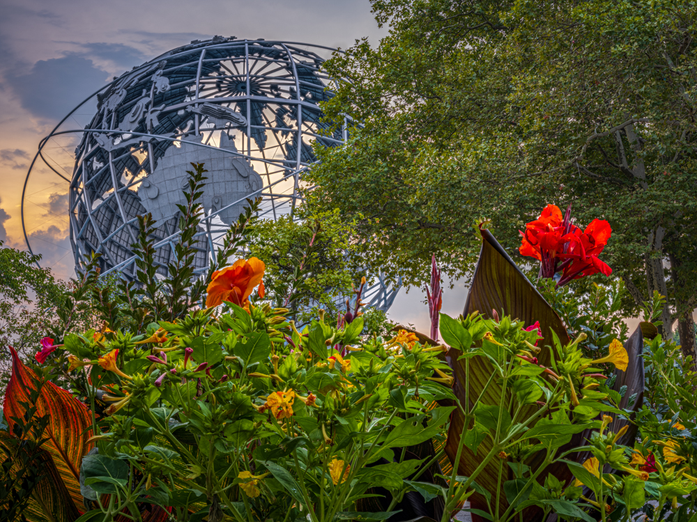 Under the shadow of the world-renowned Unisphere, the gardens of Flushing Meadows burst into life, their blooms creating a soft...